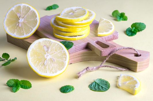Two small kitchen utensils cutting boards with slices of ripe fresh lemon and mint leaves. Ingredients for lemonade. Selective focus.