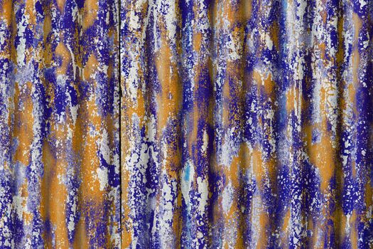 colorful motley peeled off orange nad blue paint layers on corrugated zinc coated steel sheet - full frame background and texture