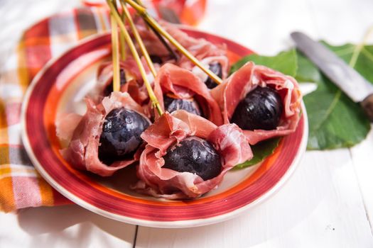 Presentation of dish skewers with ham and figs blacks