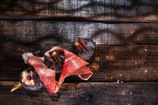 Presentation of skewers with prosciutto and figs blacks
