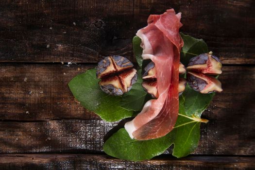 Presentation of skewers with prosciutto and figs blacks