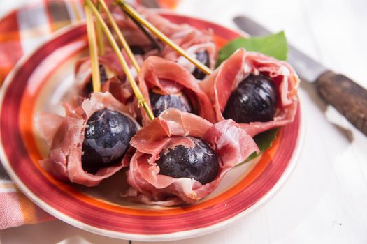 Presentation of dish skewers with ham and figs blacks