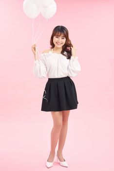 Full length portrait of beautiful romantic young woman holding white balloons isolated on pink background