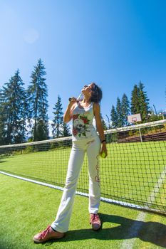 Slim gorgeous girl ready to play in tennis on court in bright summer day.