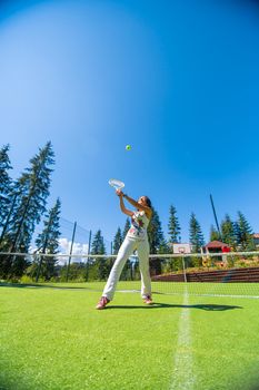 Slim gorgeous girl ready to play in tennis on court in bright summer day.