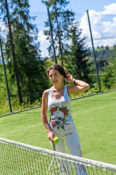 Slim gorgeous girl ready to play in tennis on court in bright summer day.
