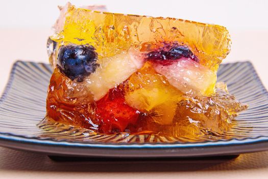 Jelly from different fruits and berries on a square saucer. Dessert. Close-up