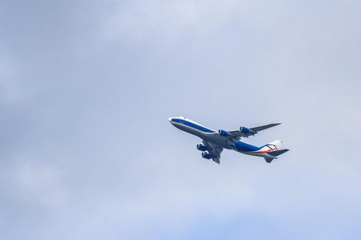 A large passenger plane makes a daily flight in the sky. The sky is clouded over