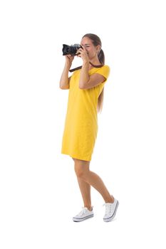 Young beautiful photographer girl in yellow dress with camera isolated on white background