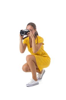 Young beautiful photographer girl in yellow dress with camera isolated on white background