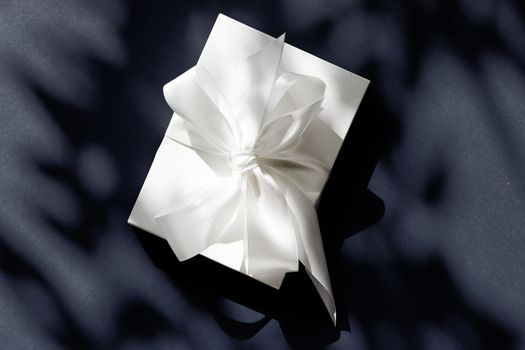 Anniversary celebration, shop sale promotion and luxe surprise concept - Luxury holiday white gift box with silk ribbon and bow on black background, luxe wedding or birthday present