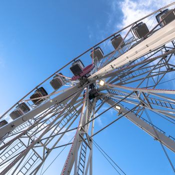 Amusement park. Ferris wheel on cloudy sky background. Bottom view. Copy space.