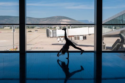 05/26/2019. Bodrum Airport / Milas Mugla Airport. Turkey. Small girl doing cartwheels exercise out of boredom while awaiting for her flight.