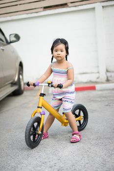 Little girl learns to riding balance bike in car park