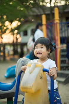little girl playing a carousel in the playground at the park