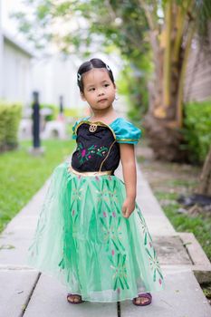 Portrait of cute little girl in princess dress standing in the park