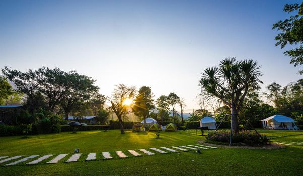 the footpath on green lawns and tent with sunrise in the garden