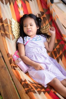 little asian girl in dress lying on cradle
