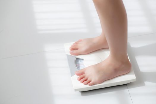 Lifestyle activity with leg of woman stand measuring weight scale for diet with barefoot, closeup foot of girl slim weight loss measure for food control and nutrition, healthy care and wellness concept.