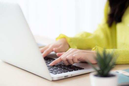 Closeup of hand young asian businesswoman working on laptop computer on desk at home office, freelance looking and typing on notebook on table, woman studying online, business and education concept.