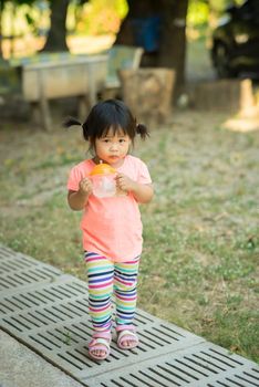 child girl hold drinking water bottle and runing in the park