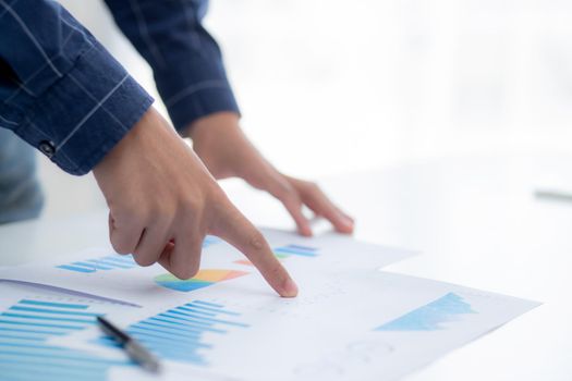 Hand of young business man pointing document data graph and chart paper, marketing and investment, report of statistics profit for financial, economic and growth of finance, management and planning.