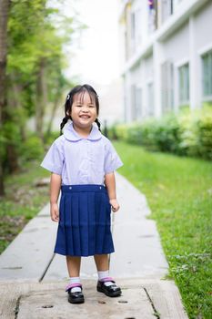 Portrait of happy little girl in Thai school uniform standing in the park and copy space,ready back to school