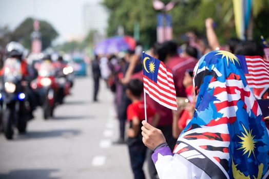 Butterworth, Kuala Lumpur/Malaysia - Aug 31 2019: A muslim girl hold Malaysian tudung and mask wave the Malaysia flag during independence day.