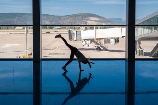 05/26/2019. Bodrum Airport / Milas Mugla Airport. Turkey. Small girl doing cartwheels exercise out of boredom while awaiting for her flight.