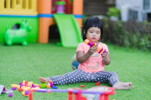 little girl playing toy colorful plastic blocks in playground