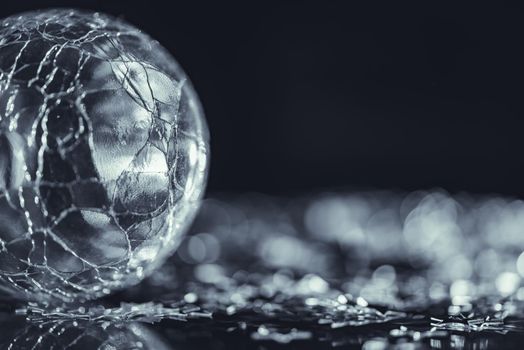 Macro photo of cracked glass sphere, bright silver star with light bokeh