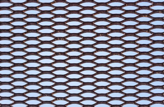 Metal rusty grid with regular pattern on blue background