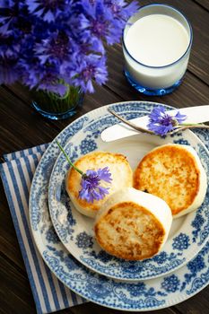 Cottage cheese pancakes with blue cornflowers, homemade traditional Belarussian and Russian cuisine. Vertical image