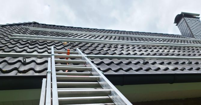 View at the roof tiles and a ladder of a residential house during roof repair