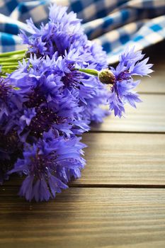 Blue flowers of cornflowers, rustic bouquet picked in summer located on wooden brown table