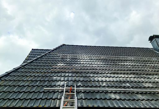 View at the roof tiles and a ladder of a residential house during roof repair