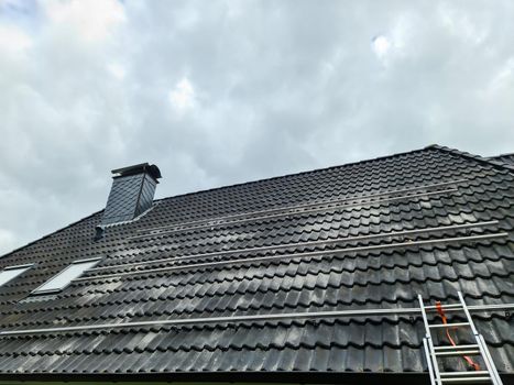 View at the roof tiles and a ladder of a residential house during roof repair