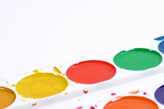 Colorful watercolor palette, top view of paintbrushes palette on white paper background