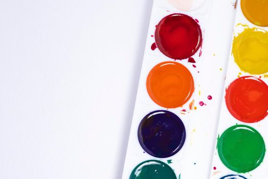 Colorful watercolor palette, top view of paintbrushes palette on white paper background