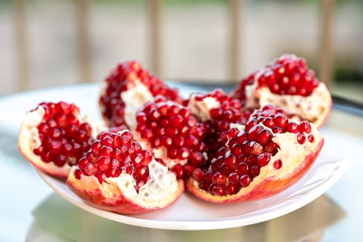 The fresh red tasty opened pomegranate on a white dish closeup