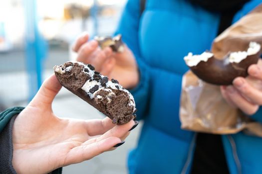 Female hands with tasty choco doughnut in the real life outdoor