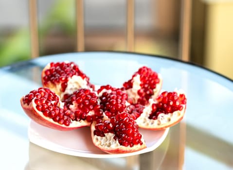 The fresh red tasty opened pomegranate on a white dish closeup