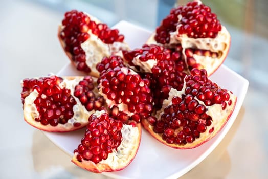 The fresh red tasty opened pomegranate on a white dish closeup