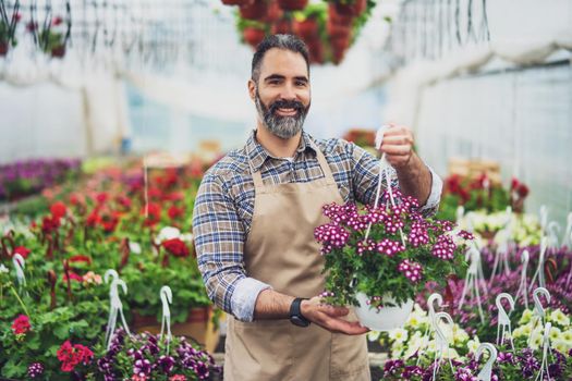 Mid adult man is owning small business greenhouse store.