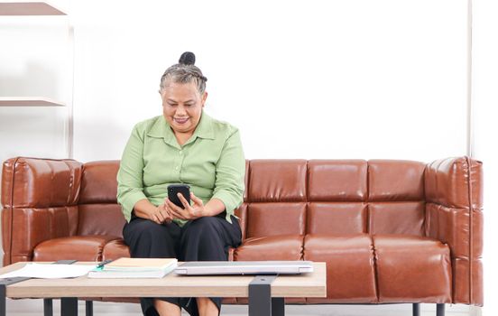 Asian women Retirement Use a smartphone and laptop in the living room concept to work at home. Quarantine to prevent spreading disease Or a conversation with someone far away Via the Internet