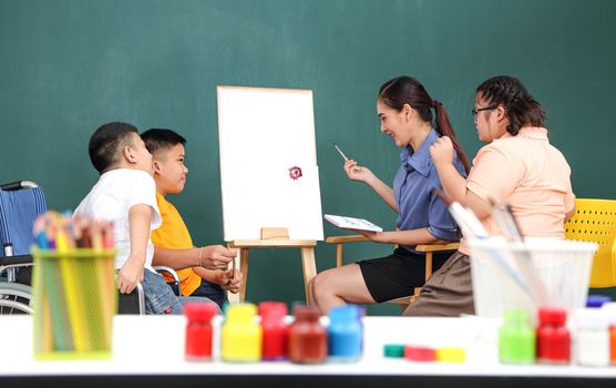 A group of young girls with disabilities and autism is training their hand and finger muscles by drawing and painting with water. With the help of teachers Happy and focused in the classroom