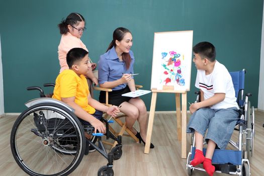 A group of young girls with disabilities and autism is training their hand and finger muscles by drawing and painting with water. With the help of teachers Happy and focused in the classroom