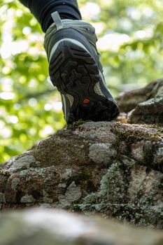 Boot of hiker on forest trail. Traveler feet are stepping on the rock . Adventure and hiking concept outdoor. Hipster lifestyle