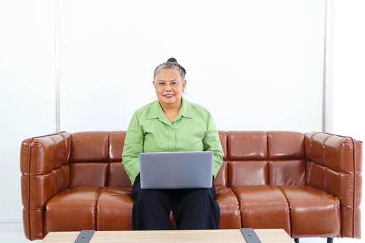 Asian women Retirement Use a smartphone and laptop in the living room concept to work at home. Quarantine to prevent spreading disease Or a conversation with someone far away Via the Internet