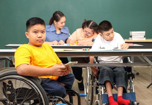 Asian disabled children Or, an autistic child learns to read, write, and train their hand and finger muscles with a teacher at their classroom desk. Concentrate and smile Happy disability kid concept